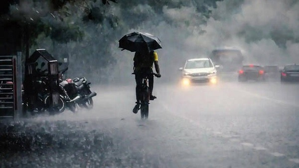 "रायपुर में भारी बारिश के दौरान भीगे हुए सड़क और छतरियों के साथ लोग।"